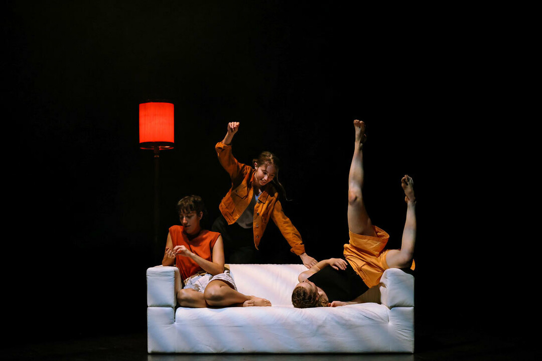 three people dancing around a sofa
