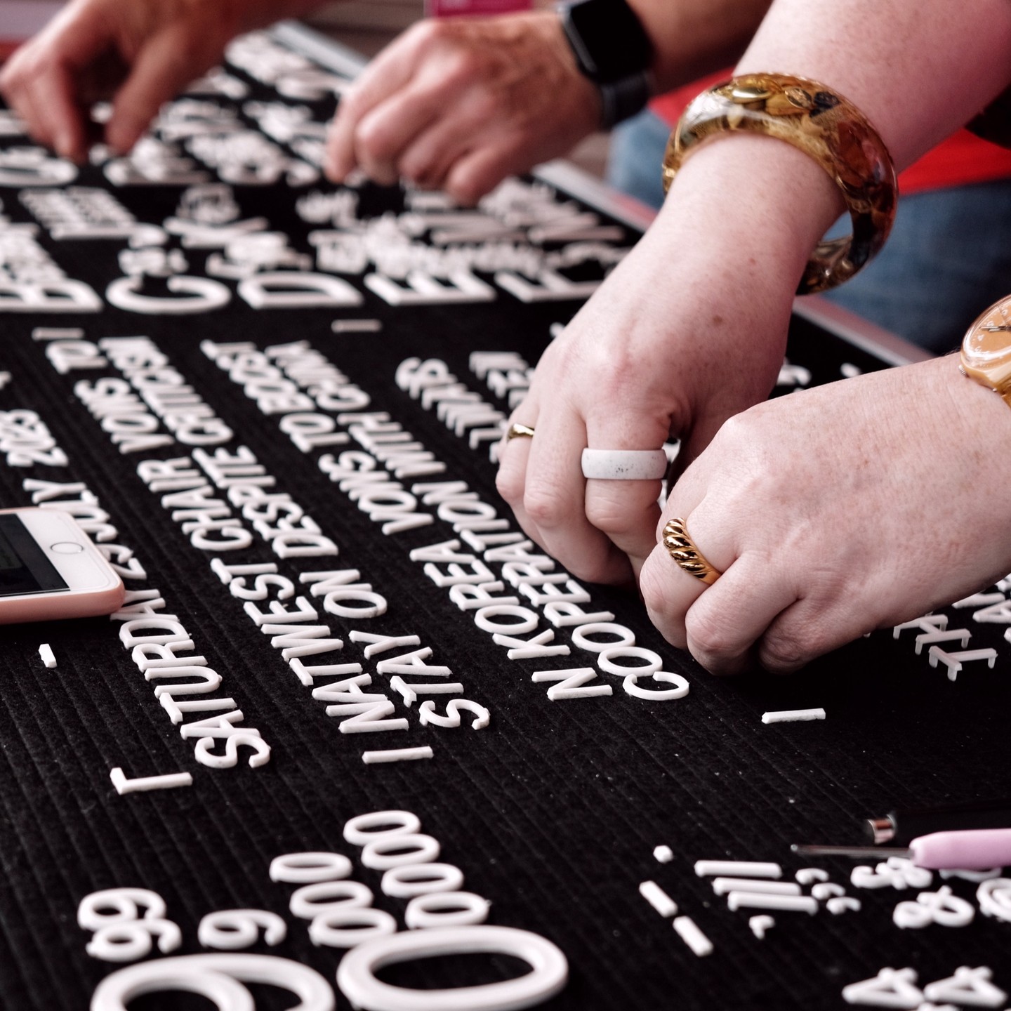 a closeup on hands moving white letters on a black board to spell out a promise as part of 'Public Trust'