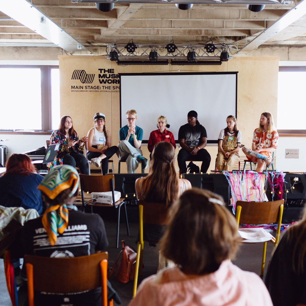 an audience watching a row of young panellists at WCID 2022