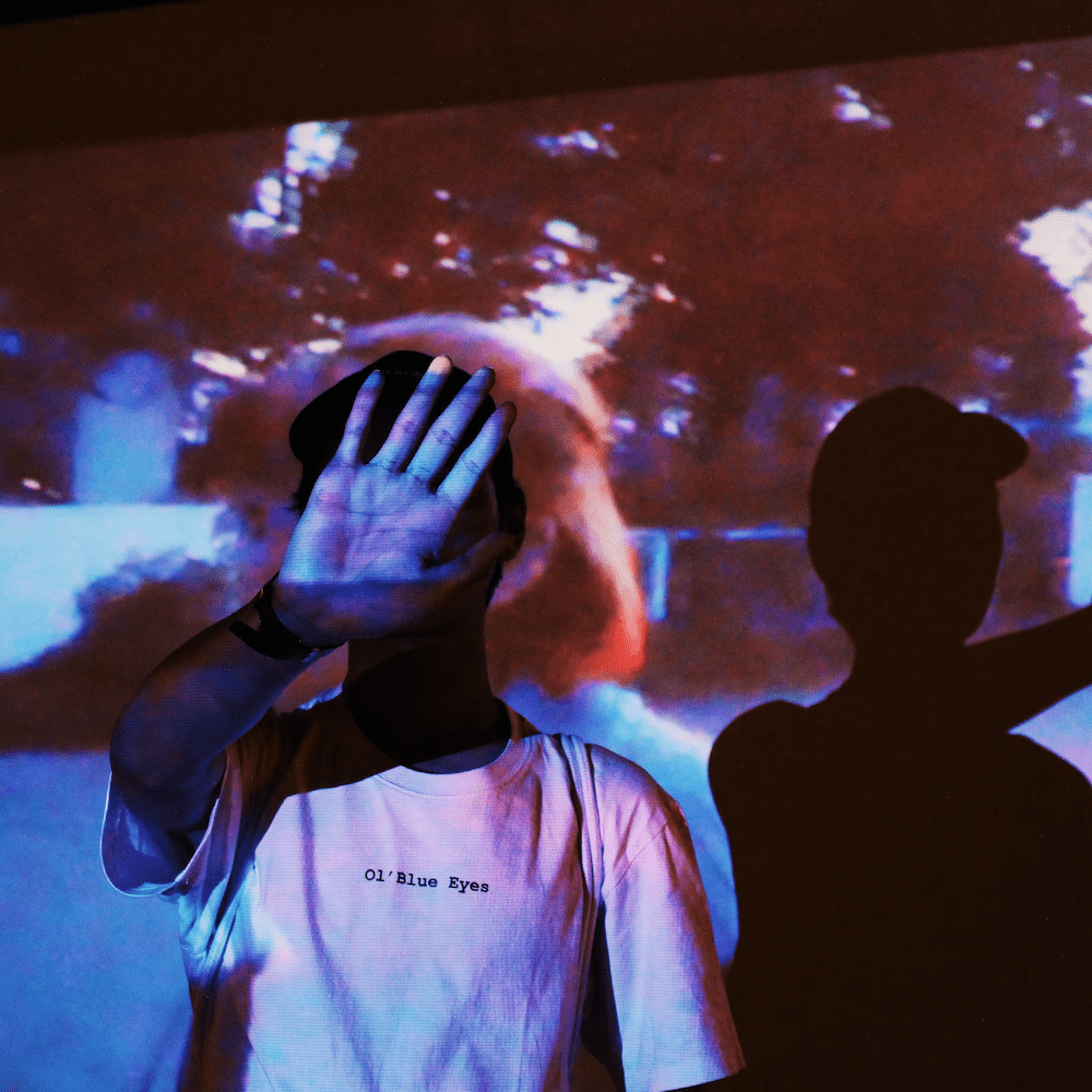 a person stood in front of the light from a projector with a hand over their face