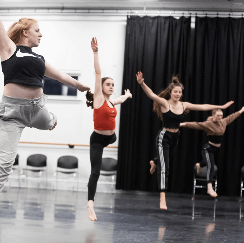 members of Strike A Light Youth Dance Company going through a routine in a dance studio