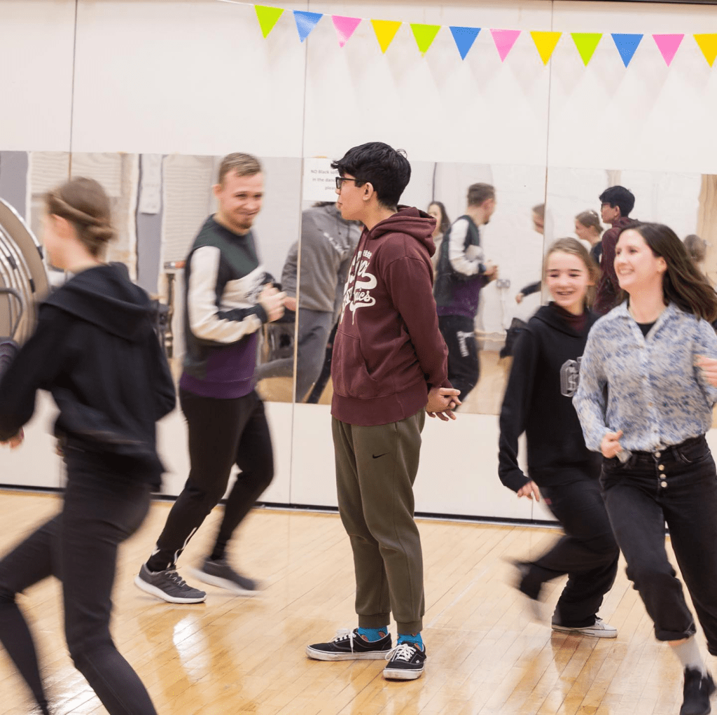 members of Strike A Light Youth Theatre running in a circle as part of a warmup activity