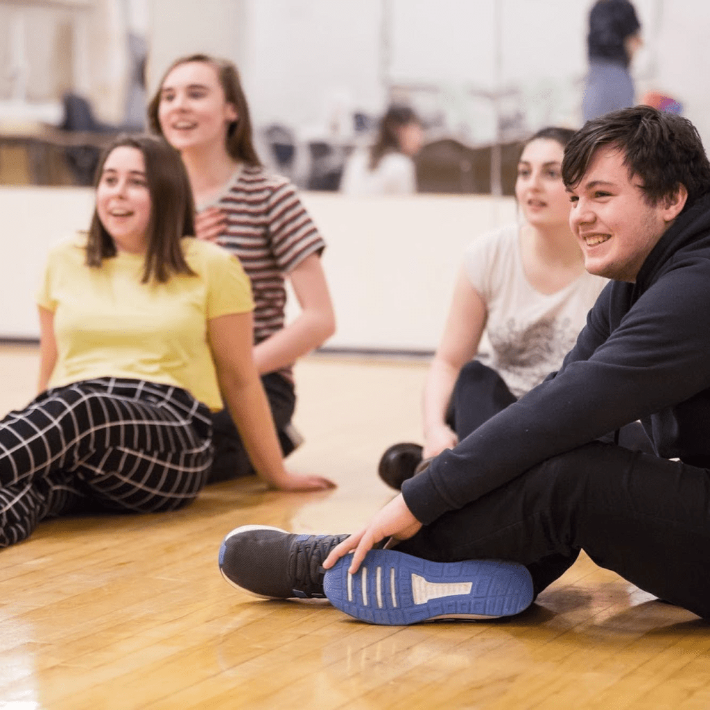members of Strike A Light Youth Theatre sat in a rehearsal studio laughing