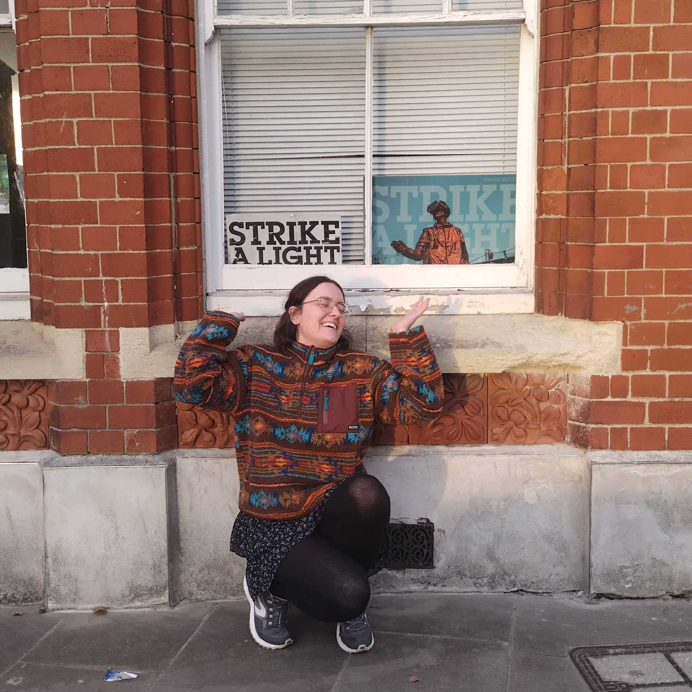 Intern Laura in front of office building with the Strike A Light sign