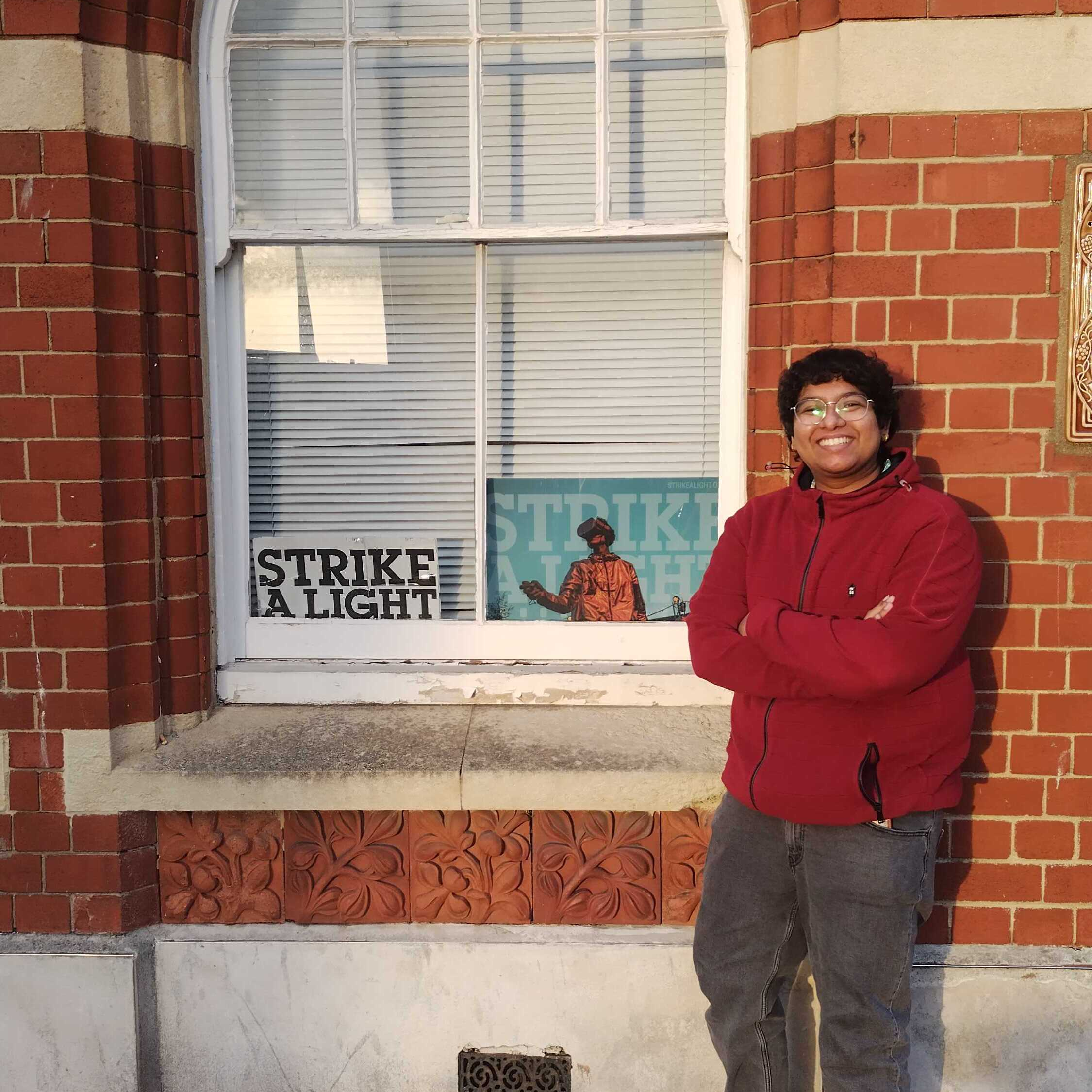 Intern Sheryl standing next to the Strike A Light sign outside of the office building
